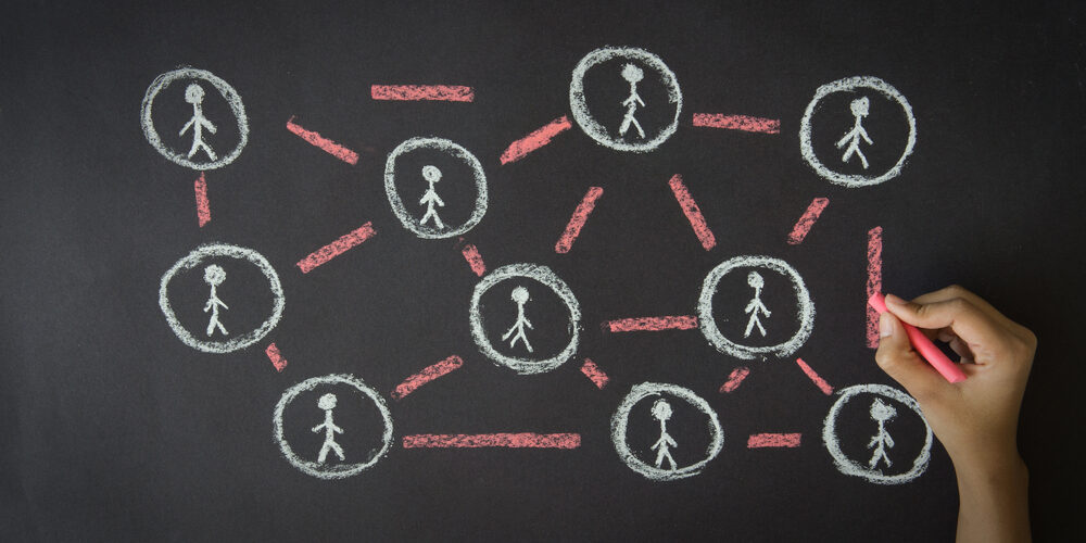 Person drawing a People Network illustration with chalk on a blackboard.
