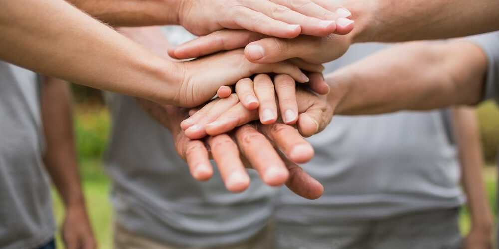 Happy volunteer family putting their hands together on a sunny day